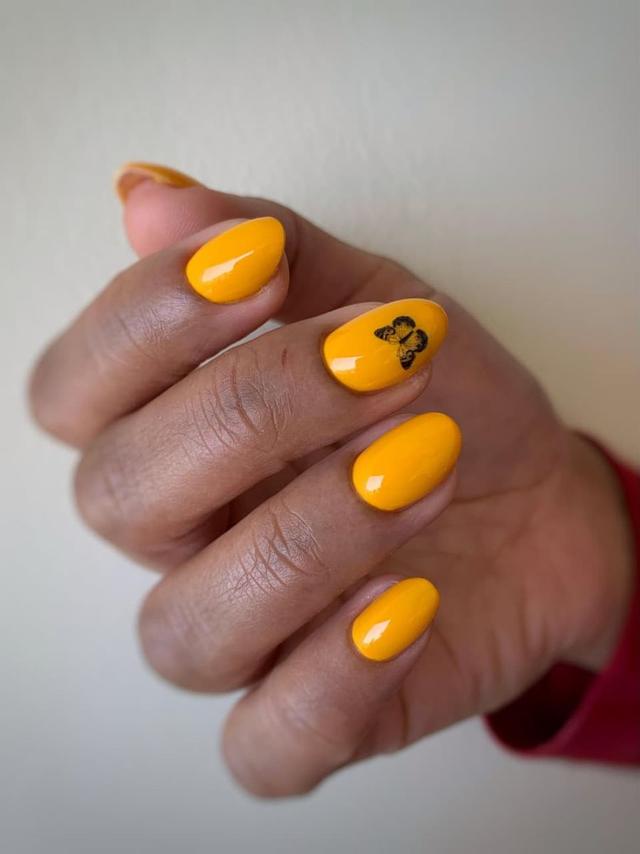 Marigold manicure with butterfly accent